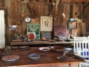 The Garden Shed is where the day’s harvested produce is stored, and where ingredients are allowed to dry or ripen. On the table are bowls and plates of beans and corn.