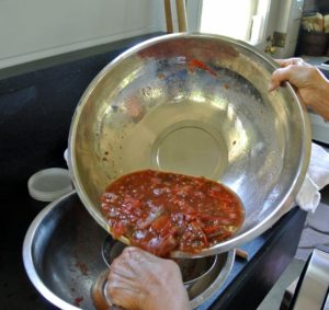 Laura pours the juicy flesh into a sieve over another bowl.