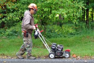My outdoor grounds crew foreman, Chhiring, keeps both hands on the edger handle at all times when it is running. Here he is guiding the machine slowly along the carriage road, keeping the blade tight against the paved surface, so it cuts through the earth.