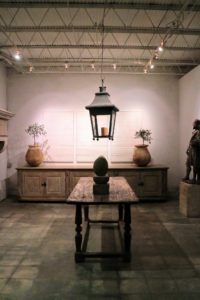 In the back of this display is a triptych by artists, Eddy Dankers and Julie Claes. It is flanked by 18th century Biot Jars over an Enfilade de Patisserie. A 19th century Tole Lantern hangs above the walnut Renaissance table.