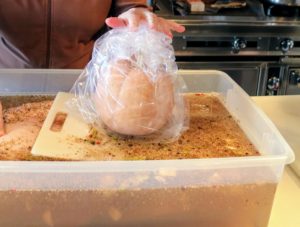 The liquid was allowed to cool before I placed the brisket in the bin. I used a  winter squash grown right here at my farm inside a plastic bag, to weigh down the brisket, so it was completely submerged in the brine.