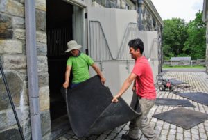 And several hours later, once the stable floors and mats are completely dry, the mats are brought back in and assembled. These mats are very, very heavy - each large piece is at least 250-pounds.