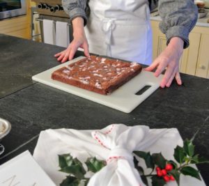 Jennifer removes the brownies from the pan and puts them on a cutting board.