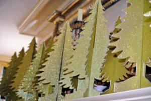Atop the mantel, cardboard trees lined up in a row.