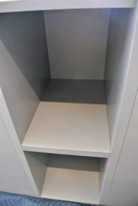 Deep shelves were installed for sweaters in a glass covered cabinet.