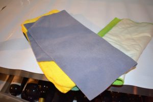 We use these microfiber cloths. Be sure not to use anything too damp or rough - it's important to keep the labels intact, especially if the bottles are old and rare.