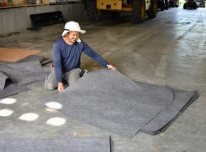 Meanwhile, Chhiring cuts weed cloth to fit the square pits - each piece, four feet by four feet. Weed barrier cloth is a geotextile with a meshed texture similar to burlap to let in water, but keep out the growth of weeds.