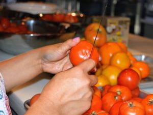 Working in batches by color, Sanu scores a shallow “x” on each tomato.