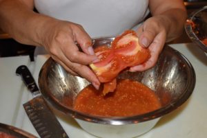 Next, the tomatoes are cut in half to expose all the seeds.