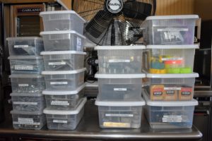 As items are properly stored, the containers are labeled and stacked ready to be returned to the closet. Labels are inexpensive and easy to affix and remove from each bin whenever needed. Ideally, use boxes and containers which are not only sturdy but stackable.