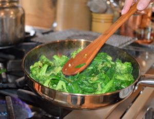 The broccoli is added to the pan first, and then the garlic and spinach.