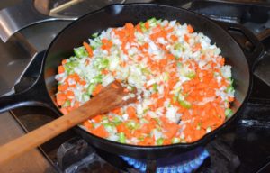 This recipe called for cast-iron. The aromatics - onions, carrots and celery - are cooked over medium high heat until they are softened and lightly browned.