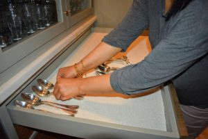 Next, Sanu carefully returns the spoons back inside the drawer, lining them up with other like pieces.