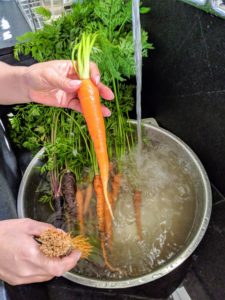 Sanu then carefully scrubs all the dirt from each of the carrots.