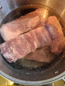 Several types of meat are used for pot-au-feu. For this dinner, Chef Pierre uses two veal shanks, two beef shanks, four pounds of boneless short ribs, one capon, bone marrow, and Saucisson a l'ail, or garlic sausage. The meats are slowly boiled in large pots to cook the meat until it is tender.