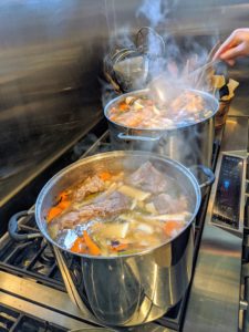 Back in the Flower Room, the vegetables and meats continue to simmer until the meat falls off the bones. Once again, Chef Pierre removes any fat that has risen to the top of the pots. It smells so delicious.