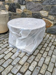 Down at the stable courtyard, this stone birdbath is first completely emptied of water. The plywood is cut to fit the top opening and then Chhiring covers the entire birdbath with a sheet of the same heavy-duty plastic.
