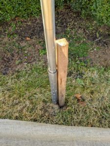 By each metal ground stake is a wooden stake. The burlap will be attached to the wooden stakes.