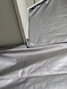The tarps, which are large sheets of strong, flexible, water-resistant or waterproof material, are pulled taut and then bolted to metal strips along the edges.
