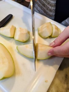 Next, she prepares the pear - she cuts, cores and divides it into large pieces.