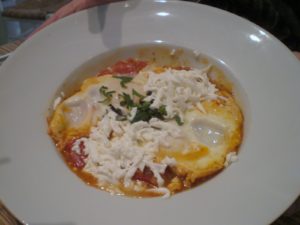 Shakshuka - a popular Middle Eastern dish - made with a chunky and spicy tomato and onion base with two eggs cooked into the mixture. This one had sheep's milk cheese melted on top.