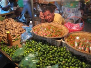 A vendor selling limes, chilies, and ginger root