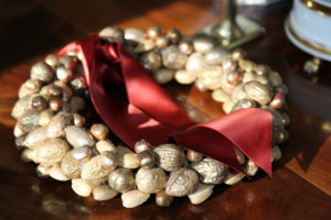 The nuts on this wreath have all been dusted with gold and sit atop a table.