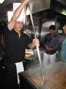 This cook, with very strong arms, is in charge of stirring the   the curry base.
