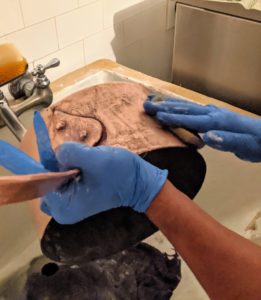 After a quick rinse with regular dish soap and water, Carlos covers the pot with cream, carefully rubbing it all over the piece. We always place a terry cloth towel on the bottom of the sink, so the metal doesn’t bang against any surfaces.