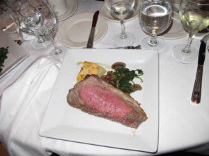 A dinner entree - New York strip steak, spinach and wild mushrooms, gruyere potato au gratin
