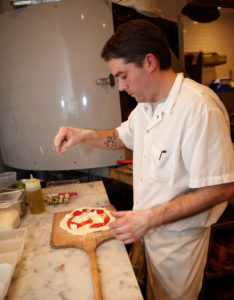 Here he is constructing a Margherita pizza.