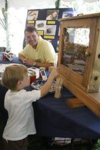 Local beekeeper, D.J. Haverkamp of Bedford Bees sitting with his exhibit - he even brought a display case of honey bees!