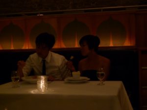 A fun young couple celebrating an anniversary - The restaurant is full of patrons, intrigued by good food, beautiful presentation, and elegant surroundings.