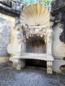 The central niche and wall fountain in the Secret Garden is surrounded by a handsome shell and framed by brackets in the form of female herms. The elaborate bench was created out of spare parts - a fountain basin, various statuary pieces, and artificial fossilised coral pieces.