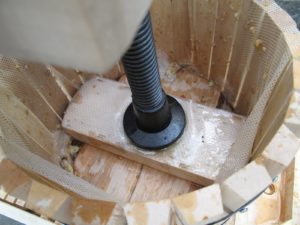 Once full of chopped apples, the tub is positioned beneath the press screw, which applies pressure to the wooden press-disc.  The mesh liner filters the juice.