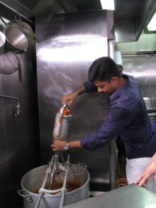 After adding the spices and the coconut milk, Visvanaath uses a large immersion blender to combine the ingredients into a smooth mix.