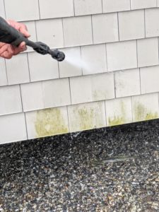 Here, Carlos uses the pressure washer to remove the algae on the cedar shake siding. The intense jet blasts away the algae and grime without hurting the paint.
