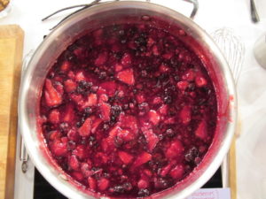 A mix of blueberries, raspberries, and strawberries simmer over medium heat.