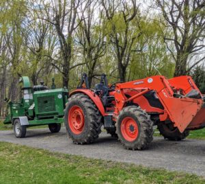 Here, the tractor is hooked up to my chipper, which is another great piece of equipment that chips twigs and branches into usable wood chips for the gardens.