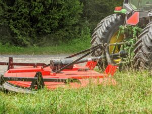 This is our bush hog. A bush hog is a rotary type of rough cutting mower that attaches to a tractor via a three-point hitch.