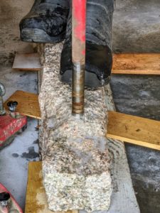 To drill through these granite posts takes time - about 15 to 20 minutes per hole. Chhiring uses his own weight to keep the post in place.