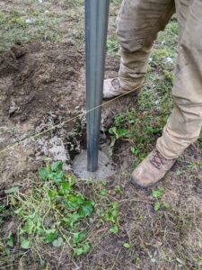 The galvanized steel posts are secured into the ground with concrete. After the posts are secured and leveled in the concrete, they're left to dry thoroughly.
