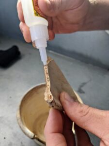 For this, Ryan uses a good, strong glue - one that can be used indoors and out and also be exposed to water. He applies glue on the pot side first, and then to the piece itself. This ensure there is coverage on both surfaces.