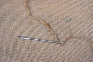 The needles are specially designed for sewing jute. These five-inch long needles have large eyes and bent tips. They're made of nine-gauge steel. Every member of my outdoor grounds crew has a needle.