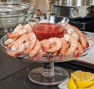 In the 1920s, during prohibition, the custom of serving shrimp in cocktail glasses began - hence the name “shrimp cocktail.” While one couldn’t drink a cocktail legally, one could at least make good use of the stemware. Shrimp served ice-cold with a sharp and tangy sauce is an unbeatable combination. Whenever I serve shrimp cocktail, I do it outdoors, so they stay cold - it is one of the most popular stations at my holiday party.