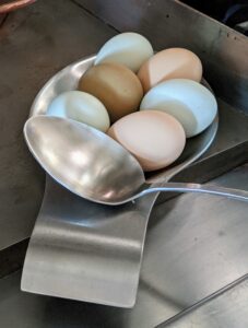 I'm using a large spoon to carefully move the eggs into the pot.
