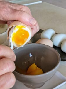To serve out of the shell, hold the egg over a small bowl, tap around center with a knife, gently pull the shell apart, and then scoop out the egg with a small spoon.