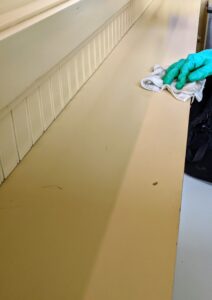 Here, he wipes down the ledge where the crew keeps small items such as hats and gloves, etc. It’s always a good idea to wear disposable gloves whenever cleaning and disinfecting surfaces - especially if using strong cleansers.