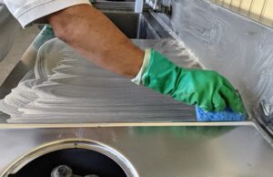 Stainless steel is a great material for kitchen areas. It is industrial strength, durable, shiny, nonporous and easy to clean and disinfect. Carlos wipes the counter with a cleaner, lets it set for a few minutes, and then rinses the surface.