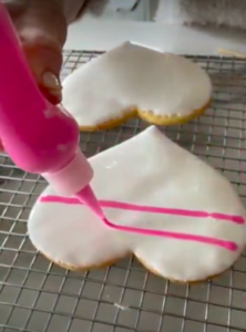 While the white frosting is still wet, I use pink icing on top. I make horizontal lines first across the cookie.